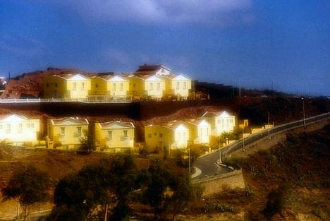 Yellow houses at sunset by a mountain road.